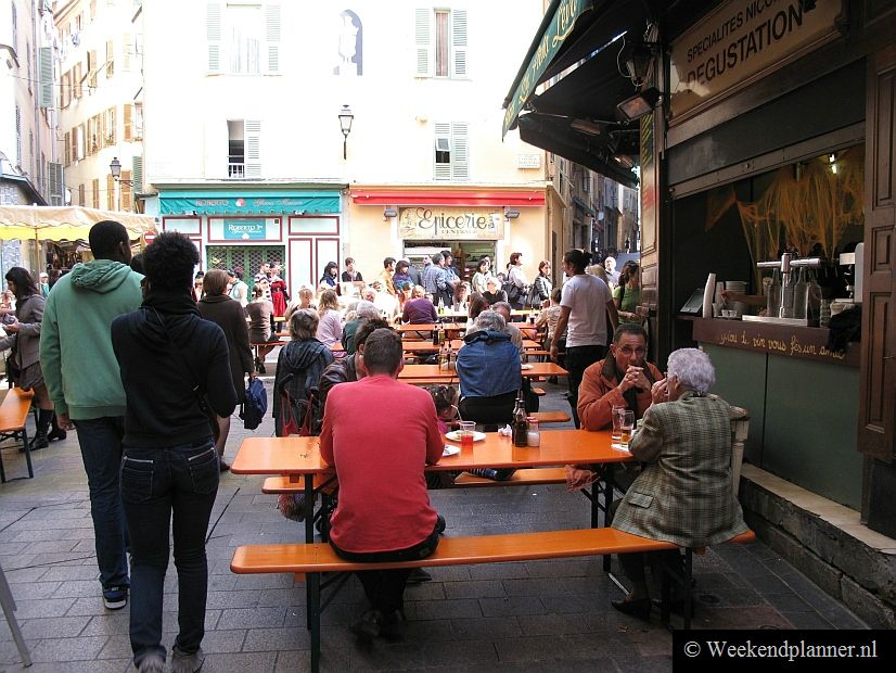 Op de Rue du Collet, vlakbij het busstation van Nice, kun je buiten zitten aan lange tafels.Tips: De attracties van het oude centrum van Nice.