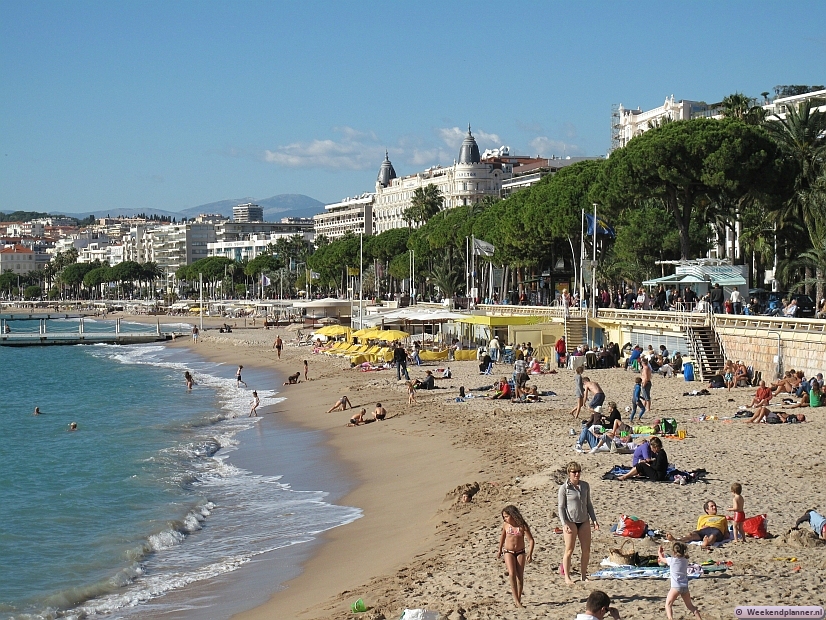 Het strand van Cannes langs de Boulevard de la Croisette. Achter de bomen aan de boulevard zie je de voor Cannes zo kenmerkende chique hotels. Tips: Een paar dagen in Cannes.