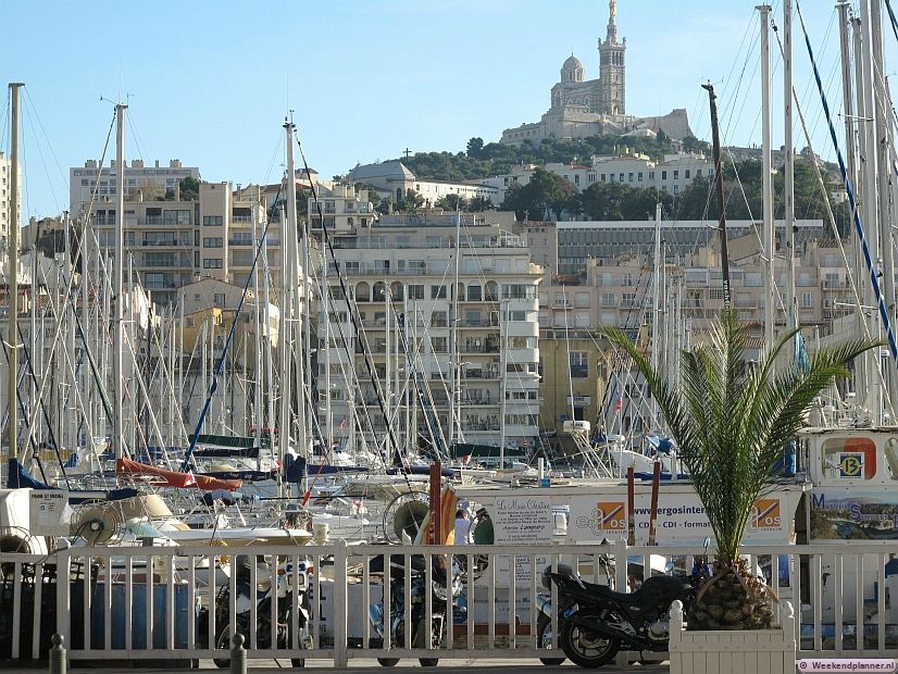 Vanuit de haven heb je een mooi uitzicht op de kathedraal Notre Dame de la Garde. De kathedraal is de meest beeldbepalende bezienswaardigheid van Marseille. Je ziet de Notre Dame de la Garde al van verre.  Foto's van de attracties van Marseille.