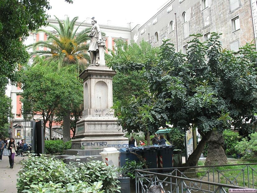 Op de Piazza Bellini liggen nog de resten van het Griekse Neapolis. Je kunt de opgravingen vlakbij dit standbeeld zien. In de buurt van het plein zijn enkele gebouwen van de universiteit en er is een conservatorium.  Foto's van het centrum van Napels.