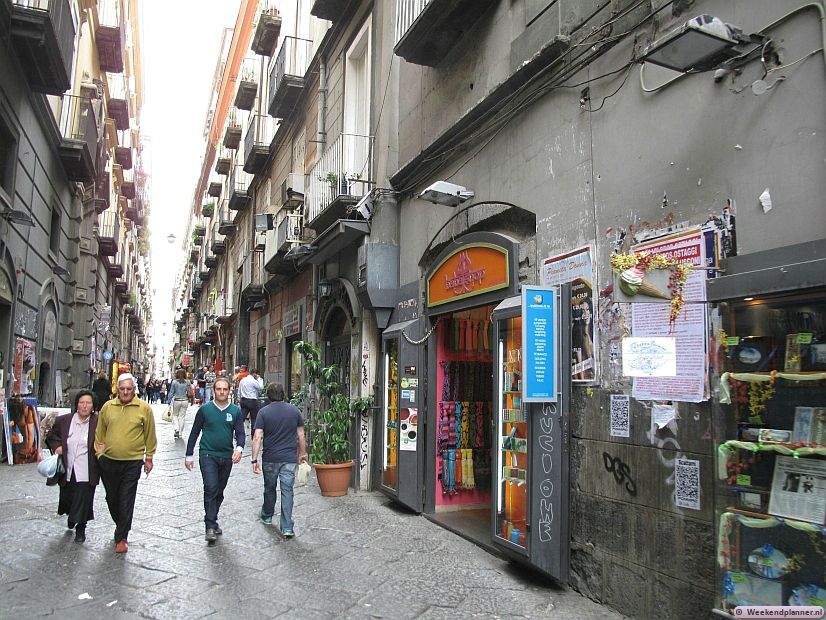 In het oude centrum van Napels gaan smalle straatjes met kleine winkeltjes over in nog smallere straatjes. Op de foto zie je de winkelstraat  Via Benedetto Croce. Tips: De attracties van Napels.