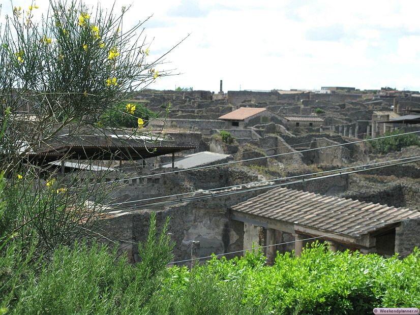 De foto is gemaakt van het huidige straatniveau. Hier kun je goed zien dat van de meeste gebouwen alleen de benedenverdieping bewaard is gebleven. Onder het landschap rond Pompeii ligt nog een deel van de stad begraven.