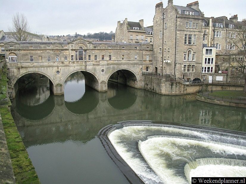 Dit is de de beroemde brug Pulteney Bridge over de rivier Avon. De brug is bebouwd met winkeltjes. Links op de brug is een leuk, maar klein, eethuisje. Het is een sfeervolle  plek voor een kopje thee of koffie. Tips: De attracties van Bath.