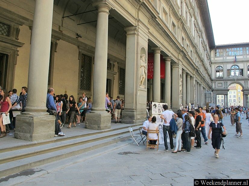 Dit is de rij van het beroemde museum het Galleria Degli Uffizi. Op de achtergrond de rivier de Arno. Het Galleria Degli Uffizi ligt naast het Palazzo Vecchio in een zijstraat. Tip: Koop je kaartjes voor musea in Florence online.  Tips: De beroemde musea van Florence.