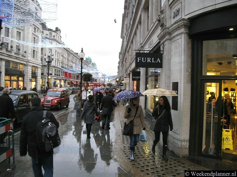 Regent Street op een regenachtige dag in december. Als het  regent in Londen en dan zijn de warme winkels en 19de-eeuwse winkelgalerijen rond Piccadilly populaire attracties.Tip: De uitverkoop in Londen.