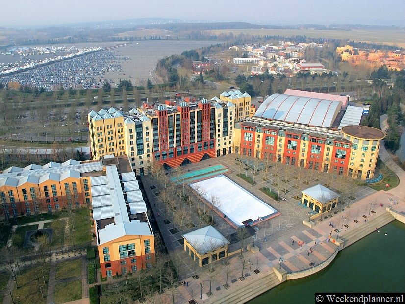 Naast de ingang van Disney Village lig Hotel New York. Op de achtergrond zie je het parkeerterrein van Disneyland. Je kunt natuurlijk ook op het station parkeren.Tips: De hotels van Disneyland Parijs.