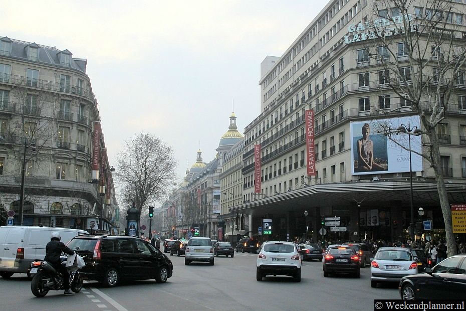 Aan de  winkelstraat Boulevard Haussman liggen de twee grootste warenhuizen van Parijs, Galeries Lafayette en Printemps. Op de foto zie je Printemps met haar torens op de achtergrond.Tips: Shoppen in Galeries Lafayette in Parijs..